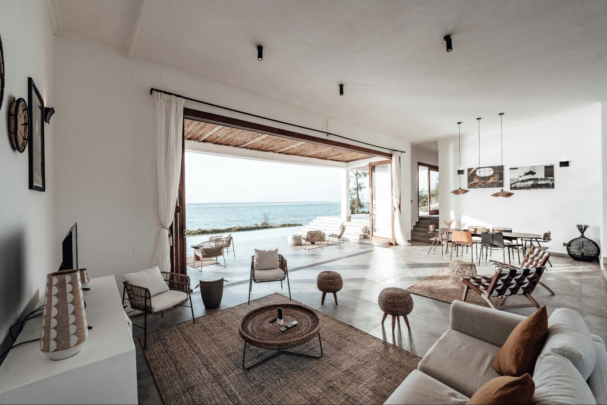 A serene coastal living space featuring open air design, organic textures and seamless indoor outdoor flow. A modern beachside interior with calming natural tones.
