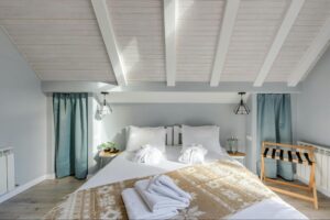 A bright and cosy modern bedroom featuring exposed beams, soft neutral tones and inviting textiles. A serene, well lit space styled for comfort and relaxation